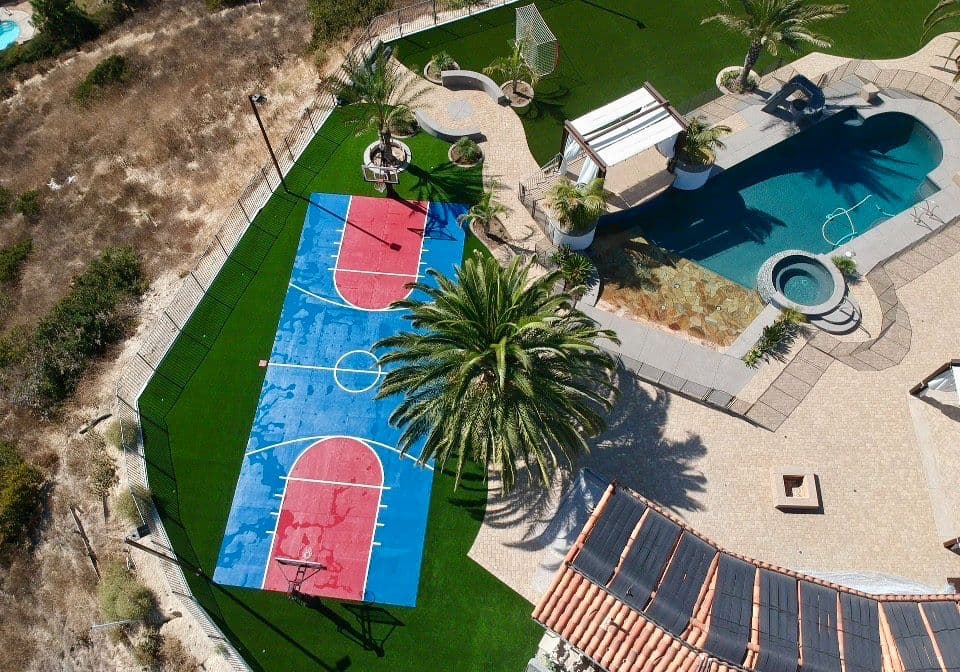 top view of a large mansion with a basketball court and a swimming pool